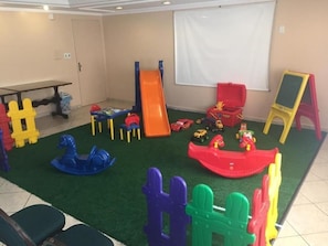 Un área de juegos infantiles con un tobogán, estructuras para escalar y coches de juguete.