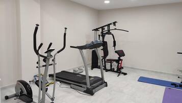 A gym with cardio equipment, a treadmill, and a bench.