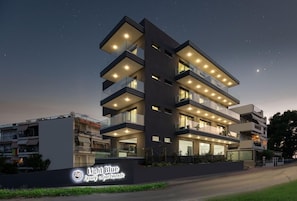Um edifício de vários andares com sacadas, uma placa indicando 'Light Blue Luxury Apartments' e fachada bem iluminada.