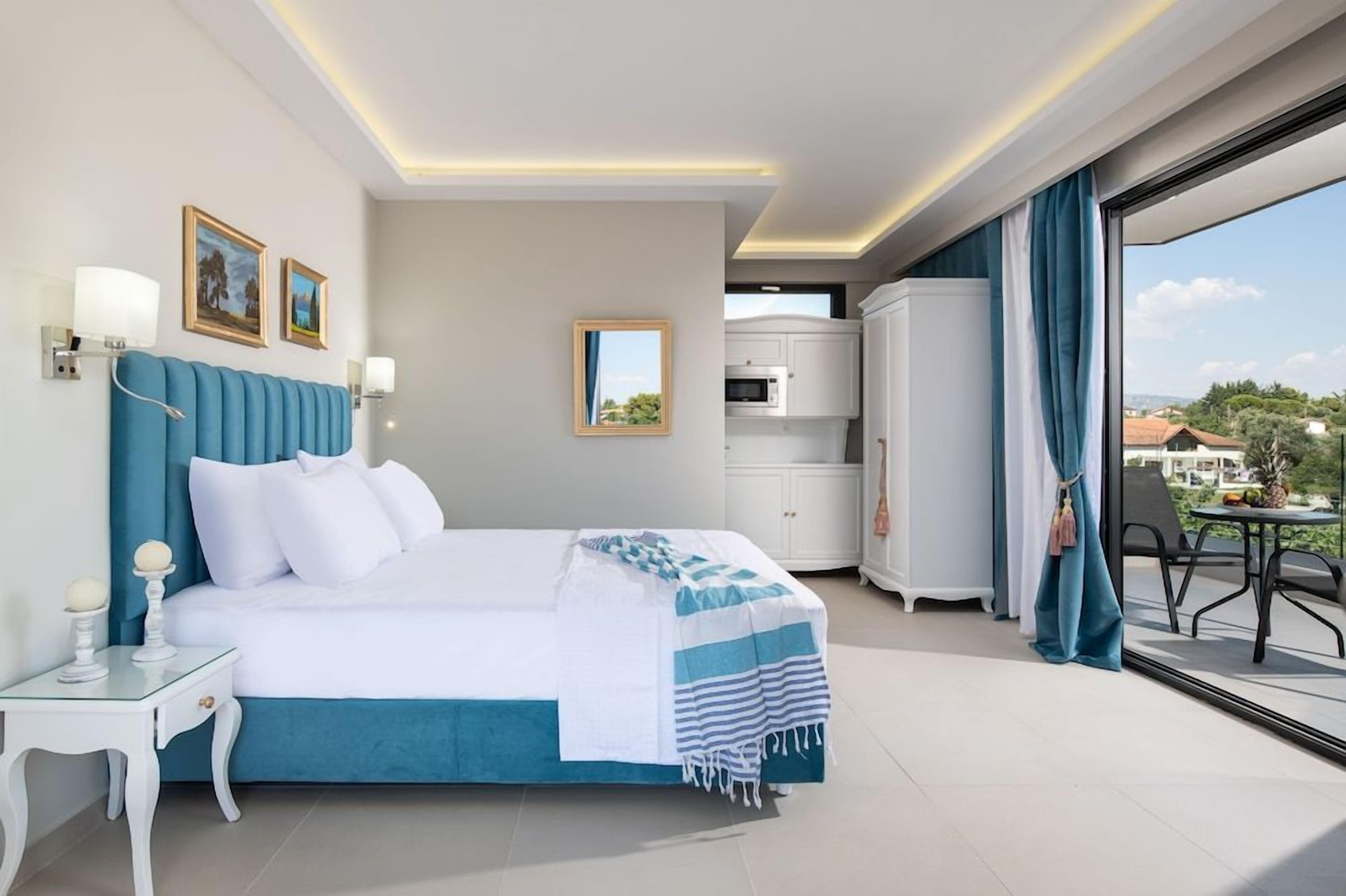 Una habitación de hotel moderna con una cama grande, un balcón con una mesa y vistas a la ciudad.
