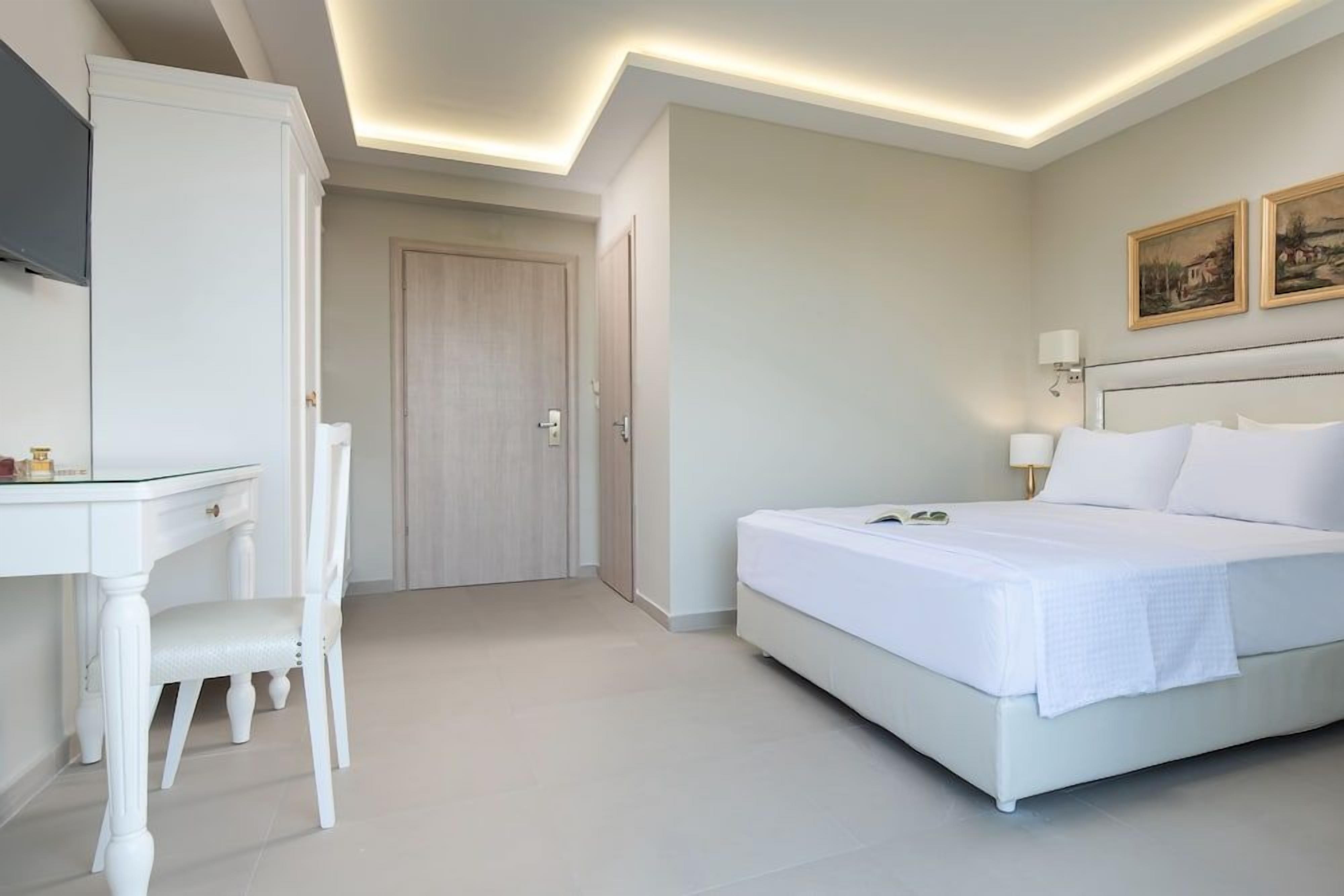 Ein Hotelzimmer mit Bett, Schreibtisch, Stuhl und Tür.
