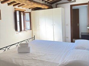 A bedroom with a bed, a wardrobe, a window, and a door. - Vrbo Property (Camigliano)