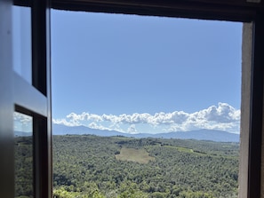 A view through a window of a landscape with trees and distant mountains. - Vrbo Property (Camigliano)