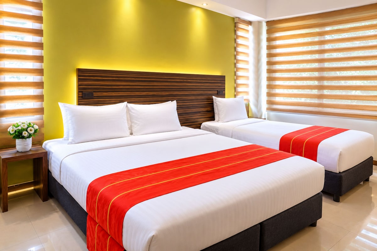 A hotel room with two beds, a wooden headboard, and a window with blinds.