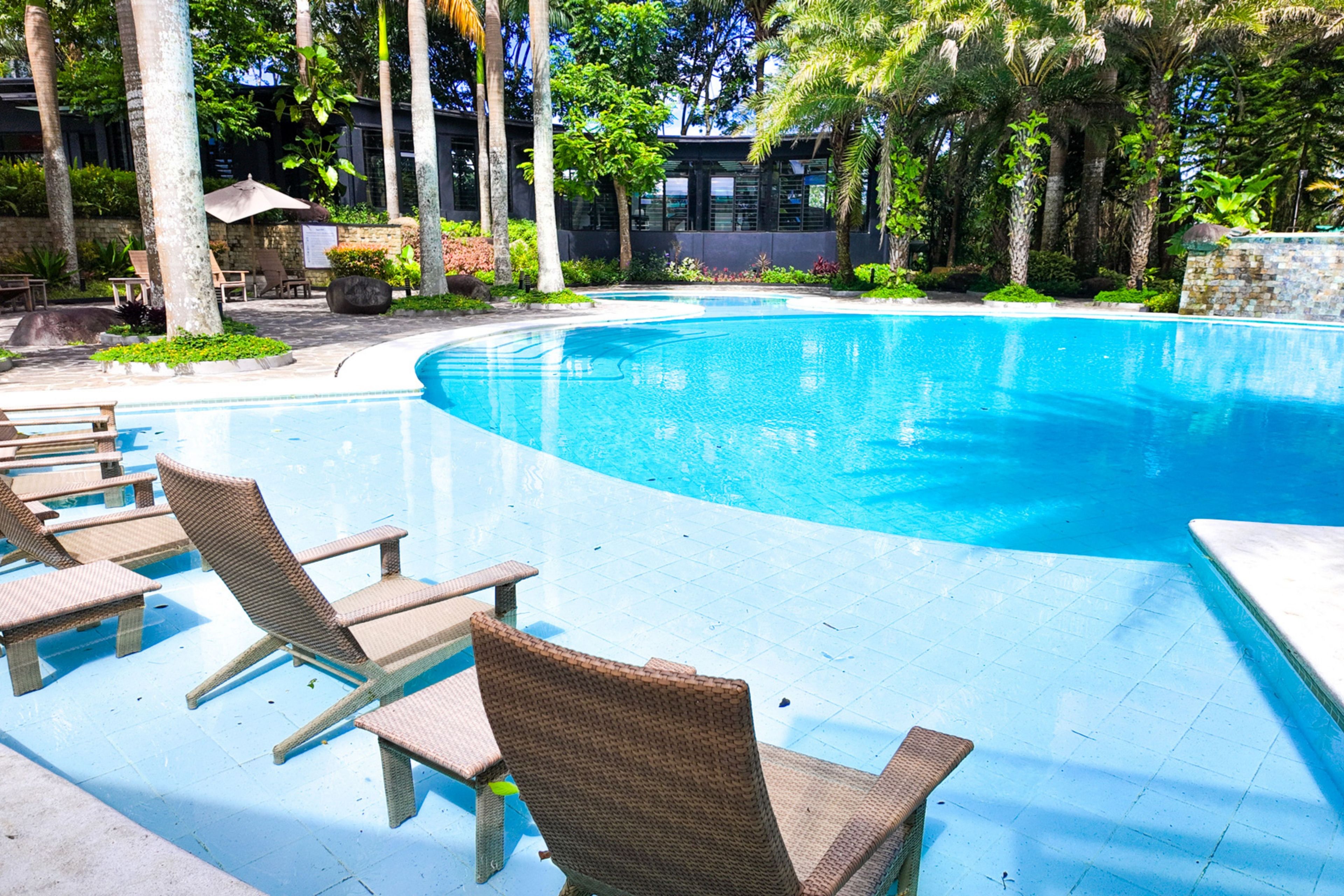 Une piscine avec des chaises longues et un mur en pierre.