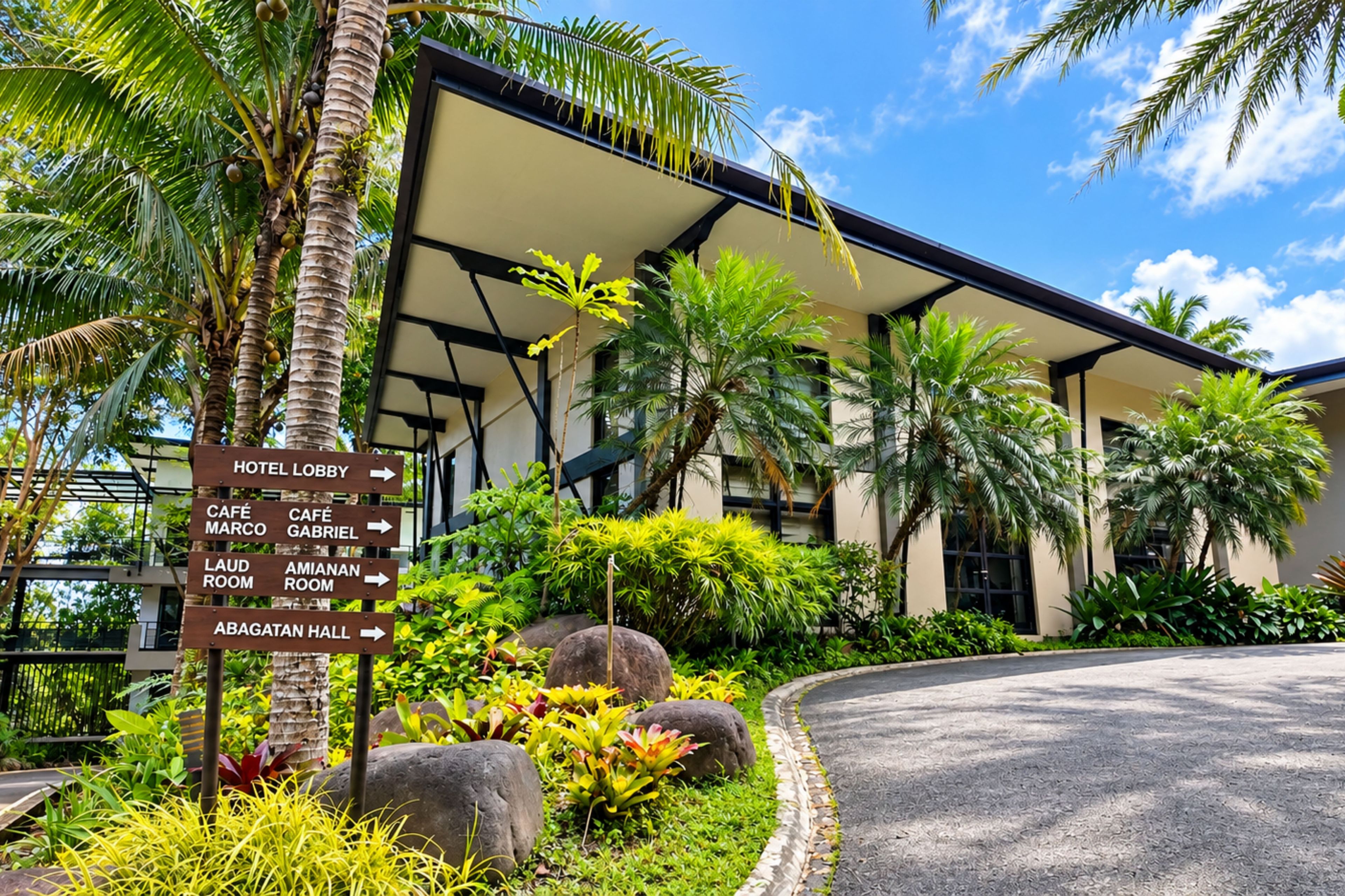 A hotel lobby with directional signs to various amenities including the lobby, café marco, café gabriel, laud room, amianan room, and bagatan hall.