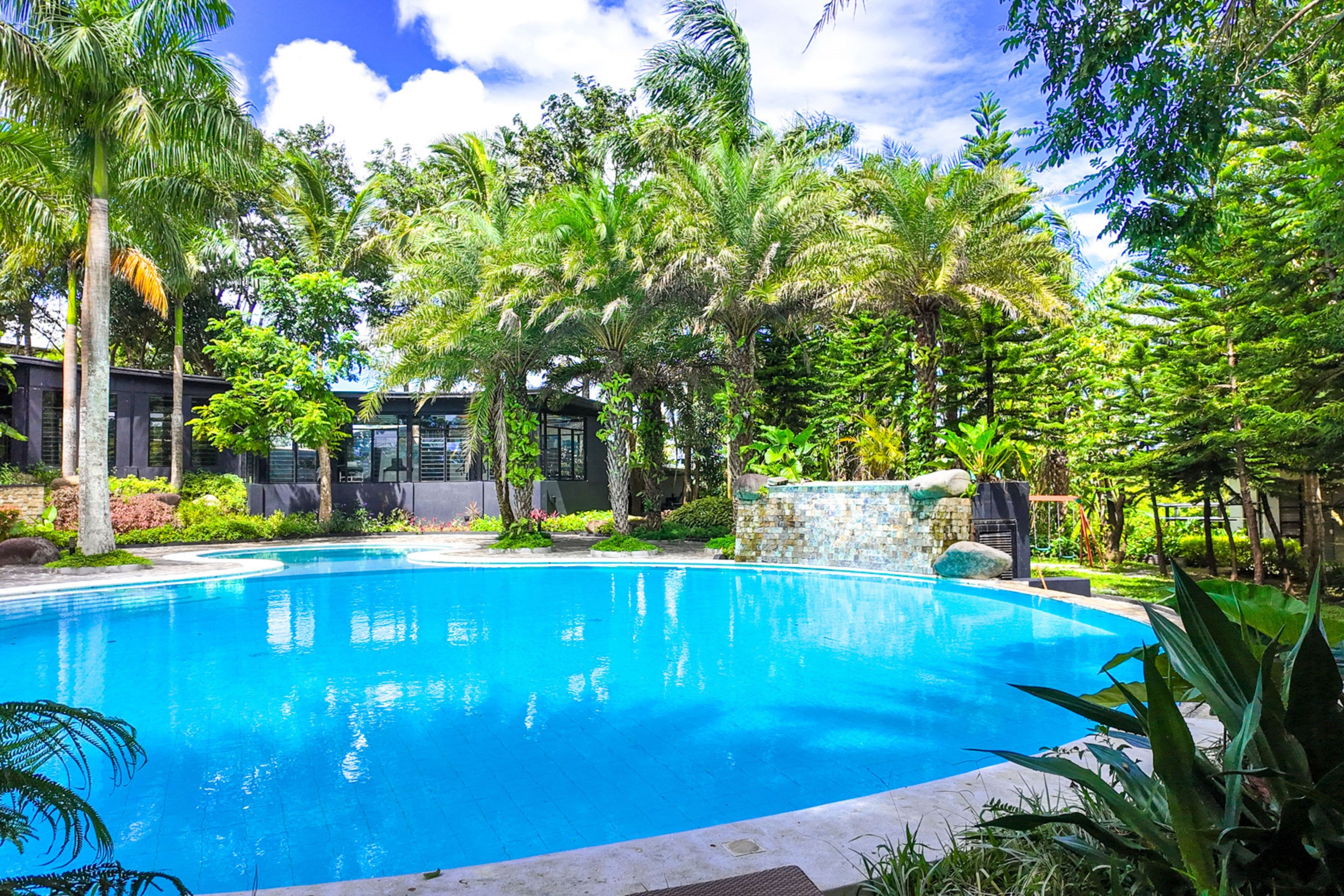 Una piscina azul cristalina rodeada de exuberante vegetación y arquitectura moderna.