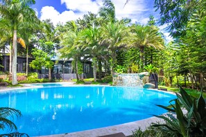 A clear blue pool surrounded by lush greenery and modern architecture. - Abagatan ti Manila Hotel and Events Place Alfonso Tagaytay (Alfonso)