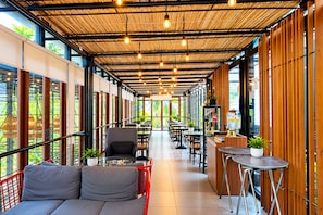 Un intérieur moderne avec un long couloir, des espaces de détente et des tables.