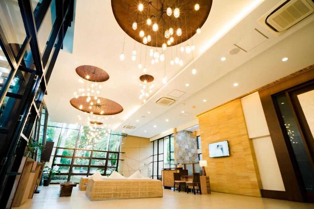 A modern hotel lobby with a large seating area, a reception desk, and a large window offering a view of the outdoors.