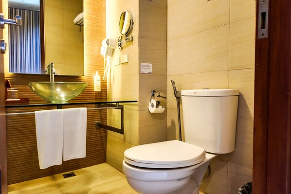 Une salle de bain moderne avec un lavabo en forme de bol en verre, des toilettes et un porte-serviettes.