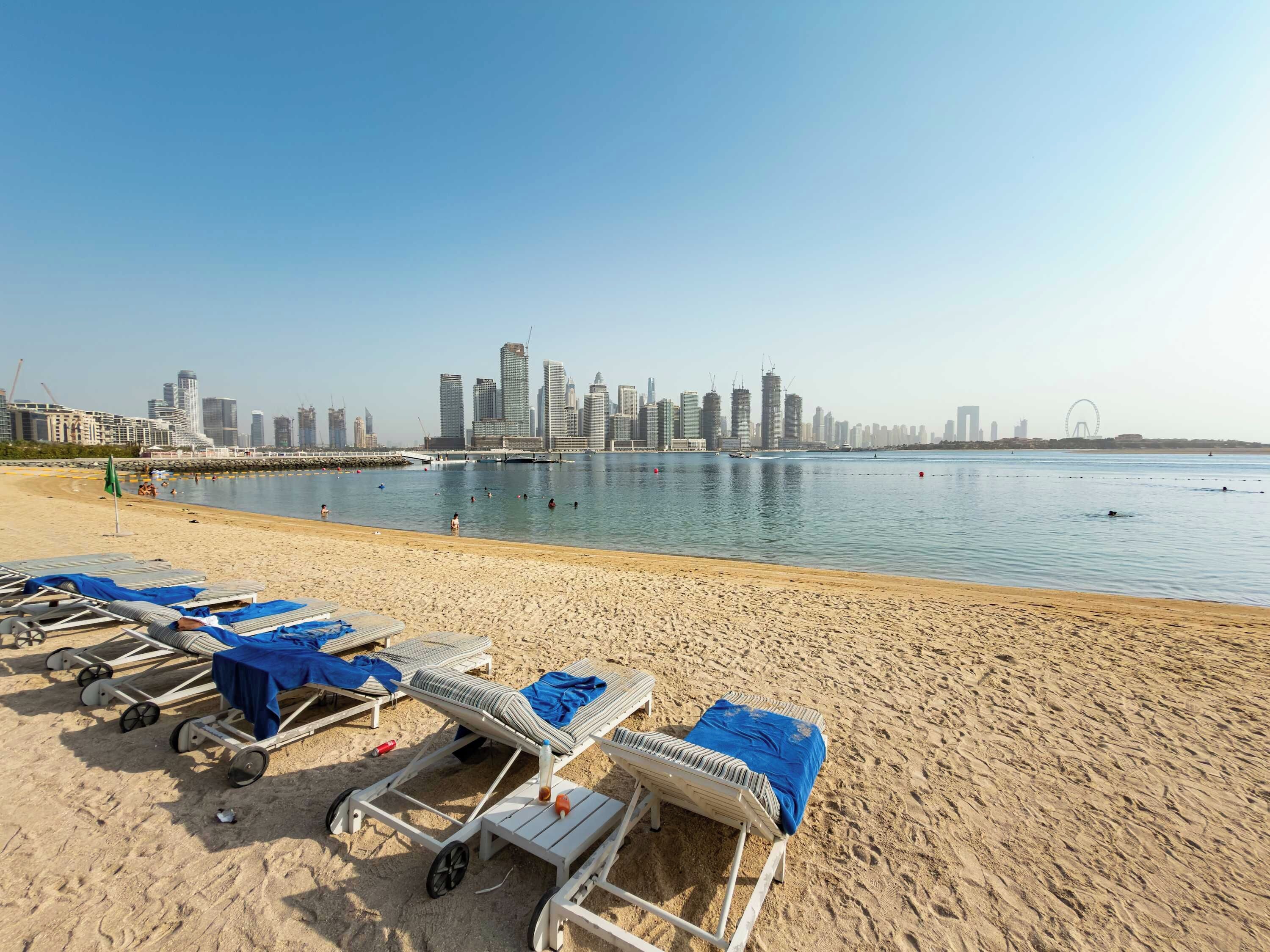 Une plage avec des transats et, en arrière-plan, la silhouette d’une ville.