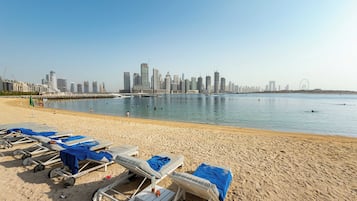 Une plage avec des transats et, en arrière-plan, la silhouette d’une ville.