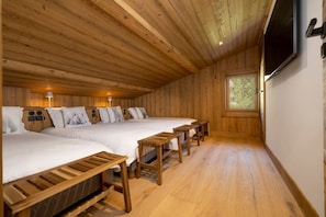 A room with two beds, wooden benches, a TV, and a window. - Tanikel - New 100-square-meter duplex | Quiet | Mountain view | Garden (Chamonix-Mont-Blanc)