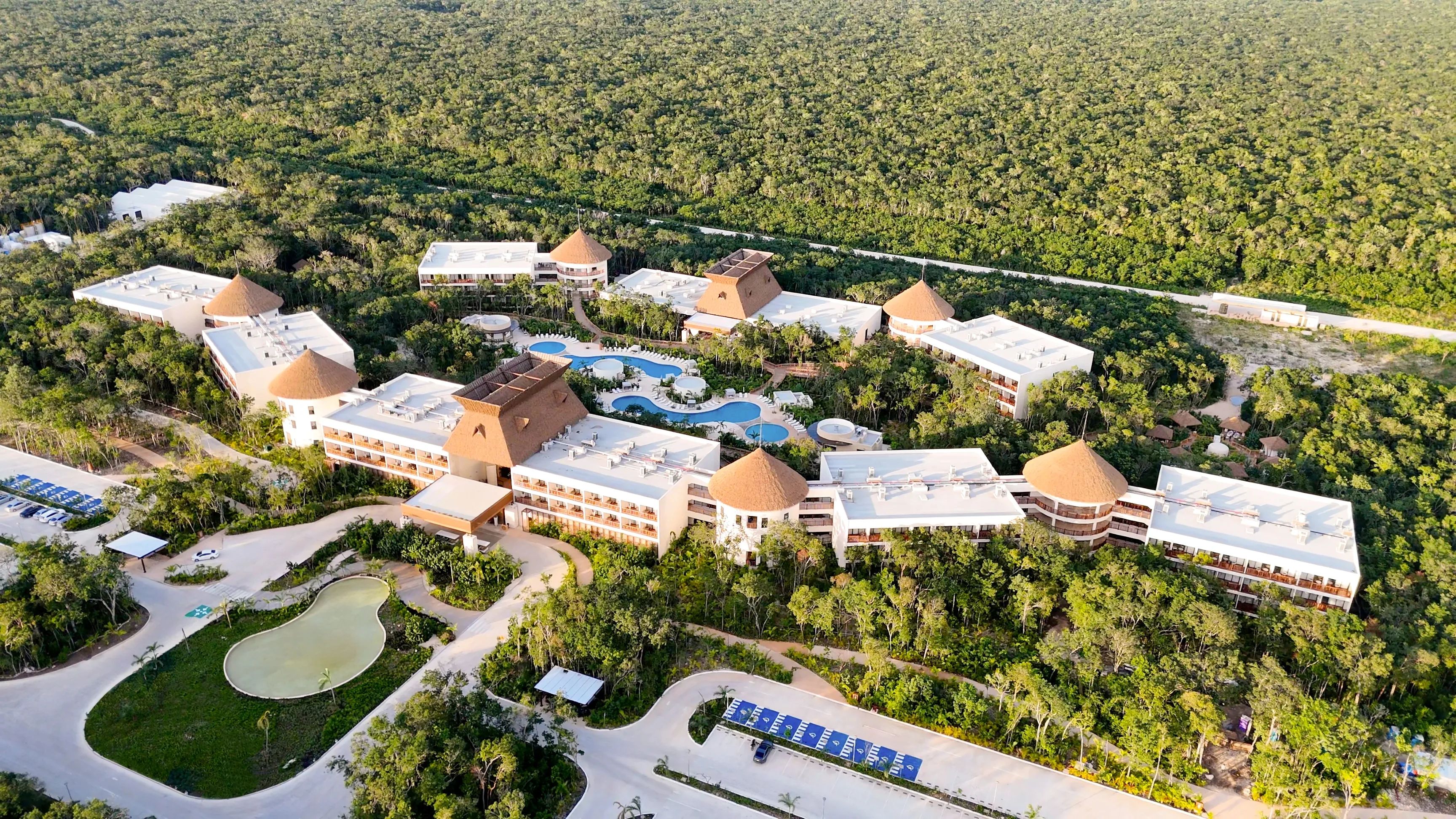 An aerial view of a resort with multiple buildings, a swimming pool, and a parking area.