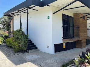 A modern building with a white exterior, black-framed windows, and a green sign indicating room number 22. - Hotel & Golf Isak (Rionegro)