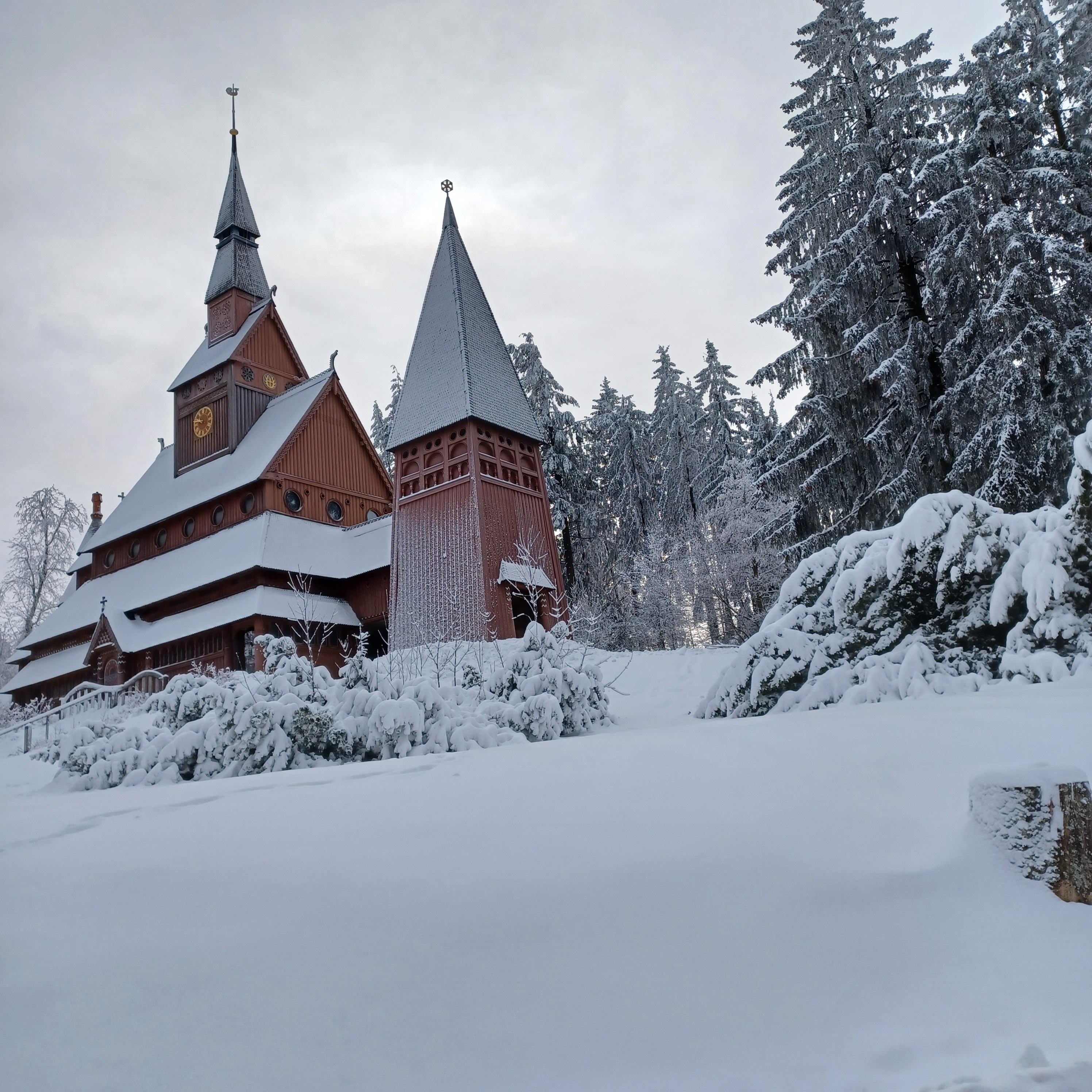 A snow-covered church with a traditional architectural style, surrounded by snow-laden trees.