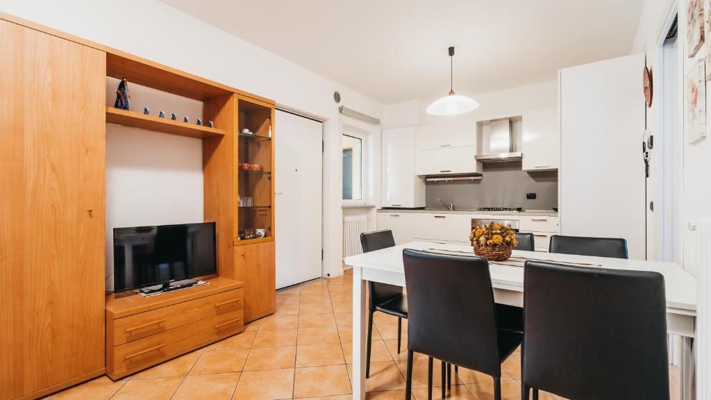 A compact kitchen with white cabinets, a dining table with chairs, and a television on a wooden stand.