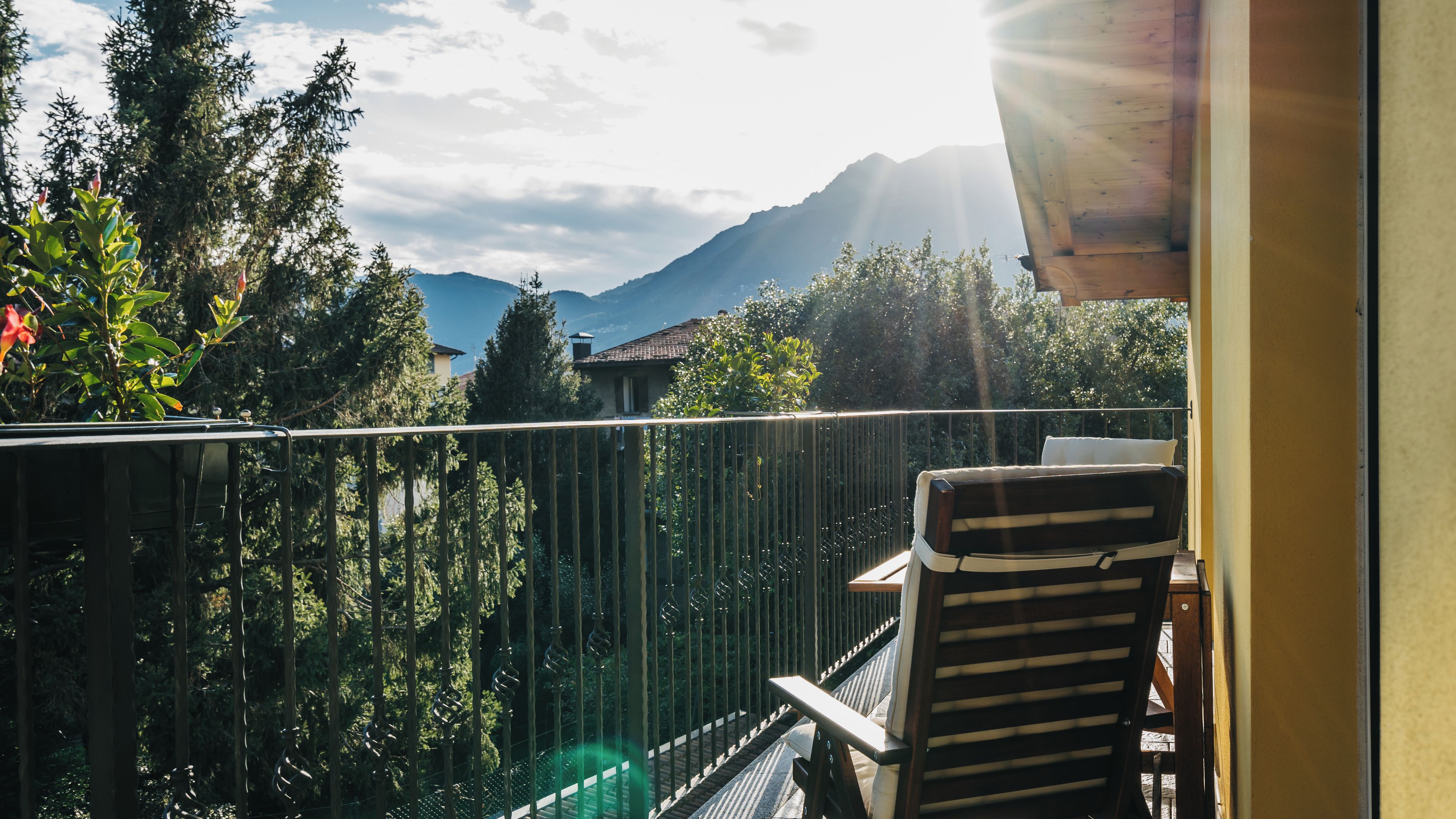 Un balcón con vista a las montañas, una silla y una barandilla.