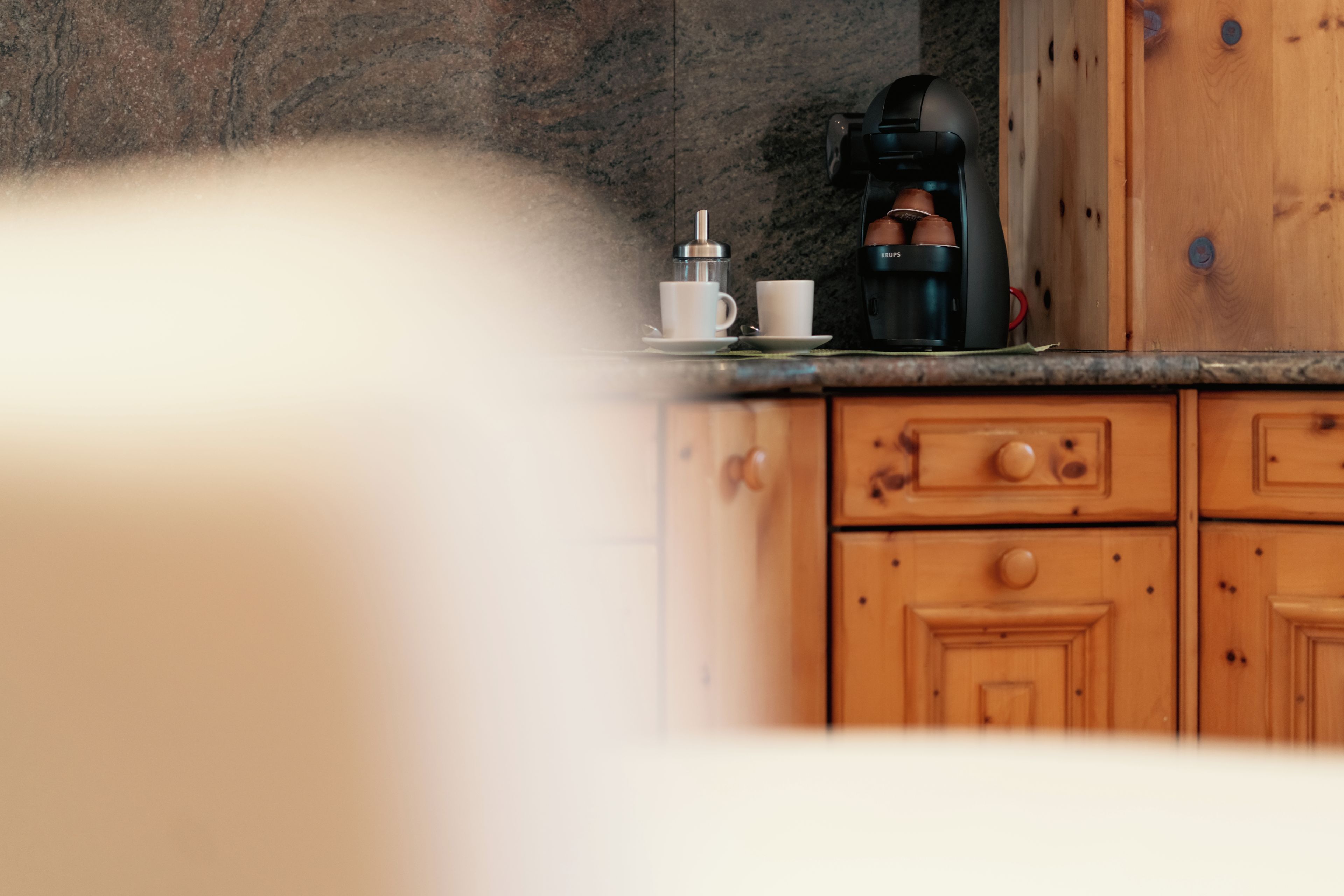 Una cocina con armarios de madera, una cafetera y una taza sobre la encimera.