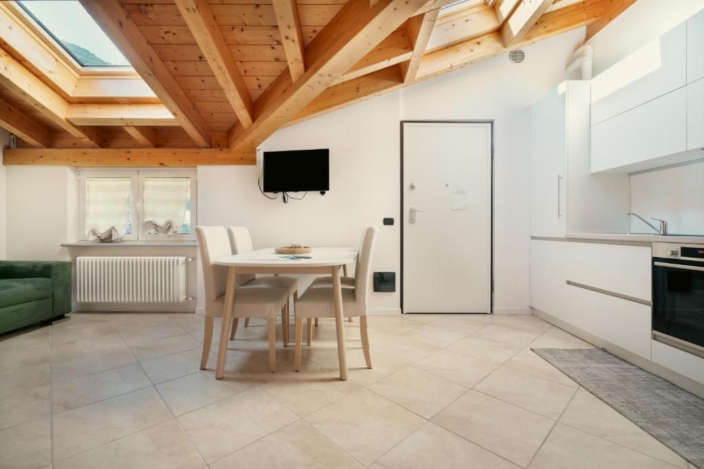 A modern kitchen with white cabinets, a dining table with chairs, a TV mounted on the wall, and a skylight above.