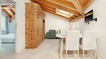 A modern interior with a dining area, wooden ceiling beams, and a green sofa.