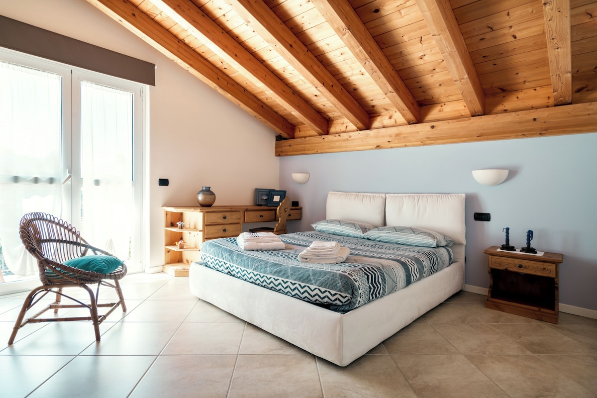 A bedroom with a bed, a chair, a dresser, and a nightstand.