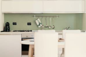 Una cocina con estufa a gas, cafetera y utensilios colgados en un colgador.