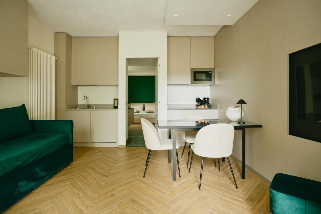 A compact living space with a kitchenette, a dining area with a table and chairs, and a green sofa.