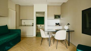 A compact living space with a kitchenette, a dining area with a table and chairs, and a green sofa.