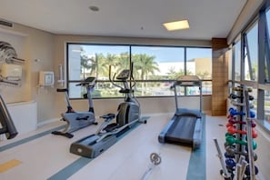 Un gimnasio con cintas de correr, elíptica y un soporte para pesas.