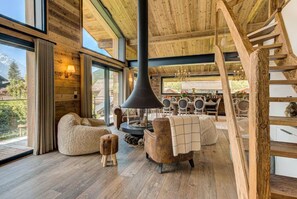 Een gezellig interieur met een open haard, houten meubels en uitzicht op het omliggende landschap.