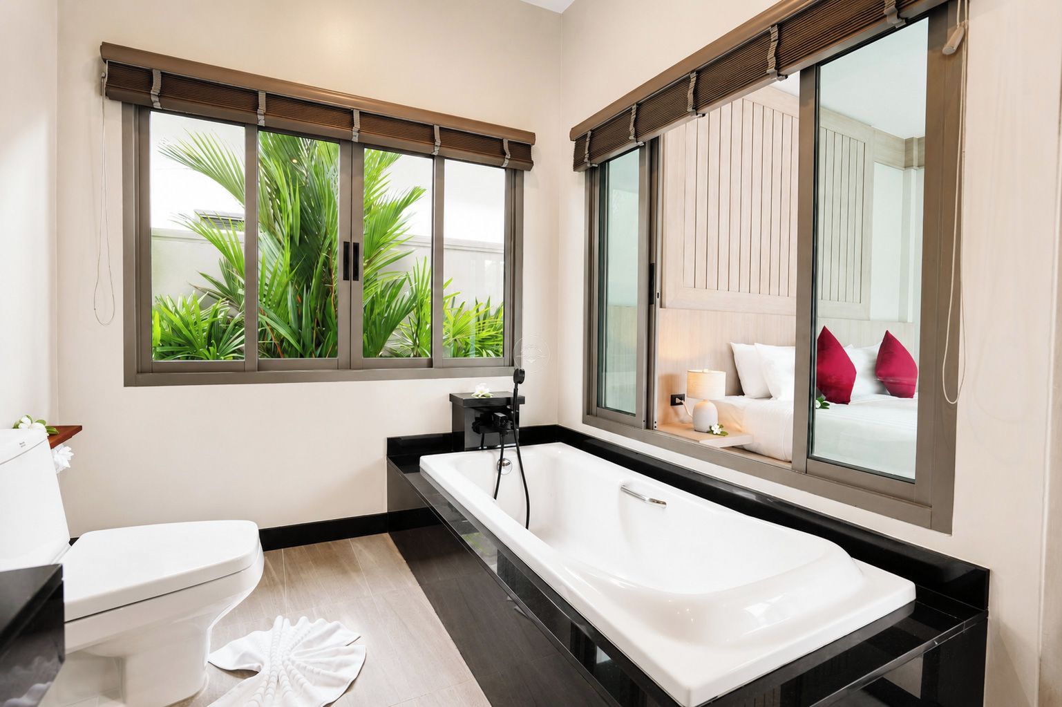A modern bathroom with a bathtub, toilet, and large windows.