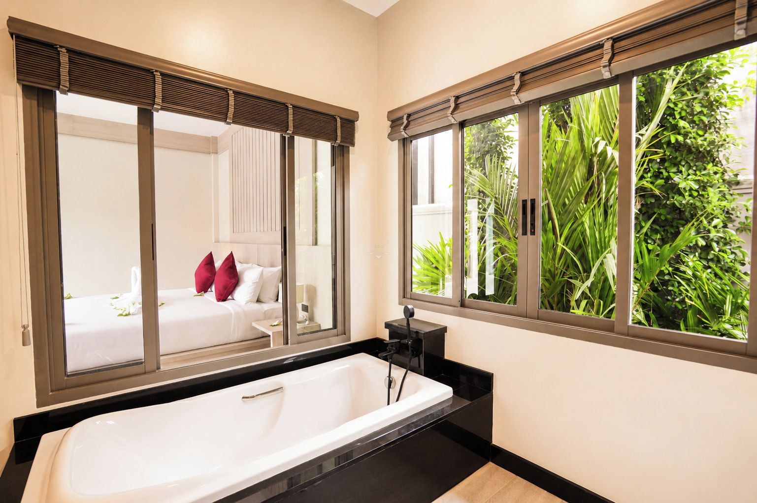 Une salle de bain moderne avec une grande baignoire, un miroir et une fenêtre donnant sur un paysage verdoyant.
