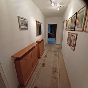 A hallway with a wooden cabinet, a mirror, and framed pictures on the walls. - Apartment '3' with Balcony, Shared Garden and Wi-Fi (Goslar)