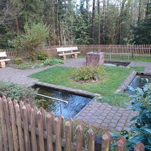 A garden with a wooden fence, a bench, a small pond, and a brick structure. - Apartment '3' with Balcony, Shared Garden and Wi-Fi (Goslar)