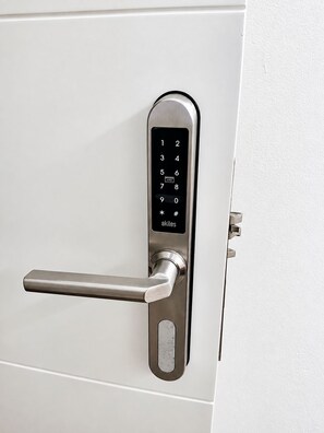 A modern door with a numeric keypad lock and a lever handle. - CasaGoa Madrid | 5-bedroom home near Madrid Río (madrid)