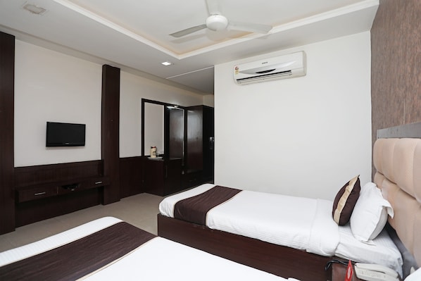 Habitación de hotel con dos camas, televisión, armario y aire acondicionado.