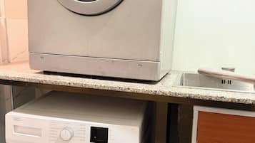 Una lavadora y secadora apiladas, con un panel de control y una etiqueta de advertencia.