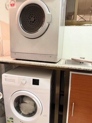 A stacked washer and dryer unit with a control panel and a warning label.