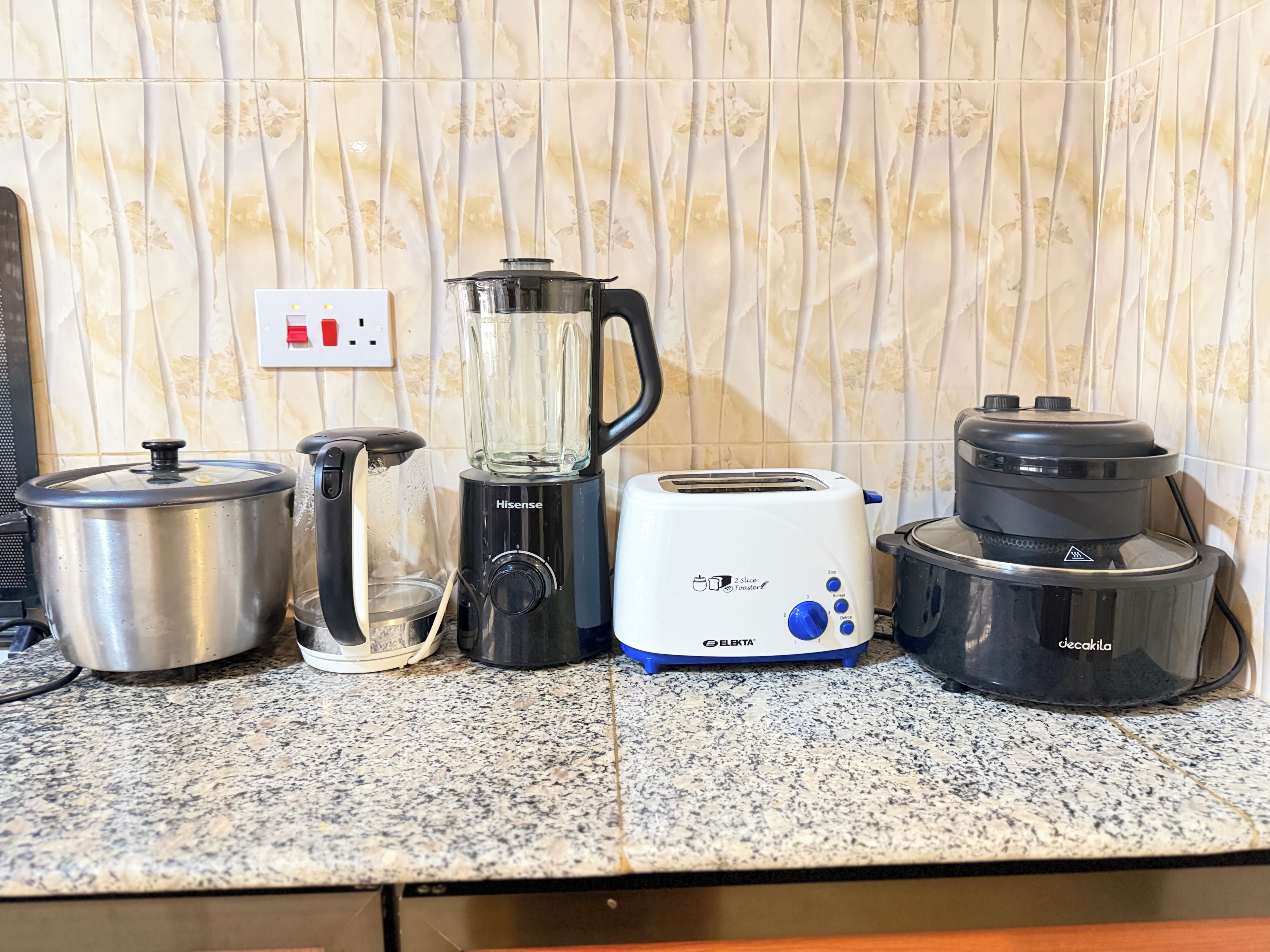 Una encimera de cocina con una olla de acero inoxidable, una licuadora, un tostador y una cafetera.