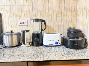Un plan de travail de cuisine avec une casserole en acier inoxydable, un mixeur, un grille-pain et une machine à café.