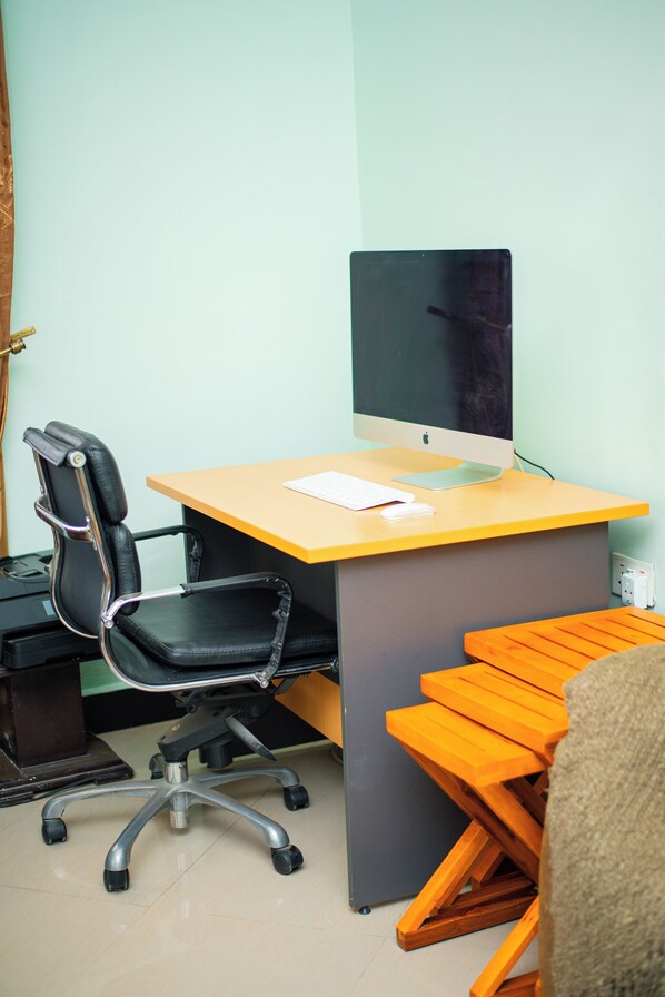 A workspace with a desk, chair, computer, keyboard, mouse, and a small table.