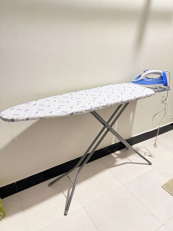 A portable ironing board with a patterned ironing board cover and a Philips iron.