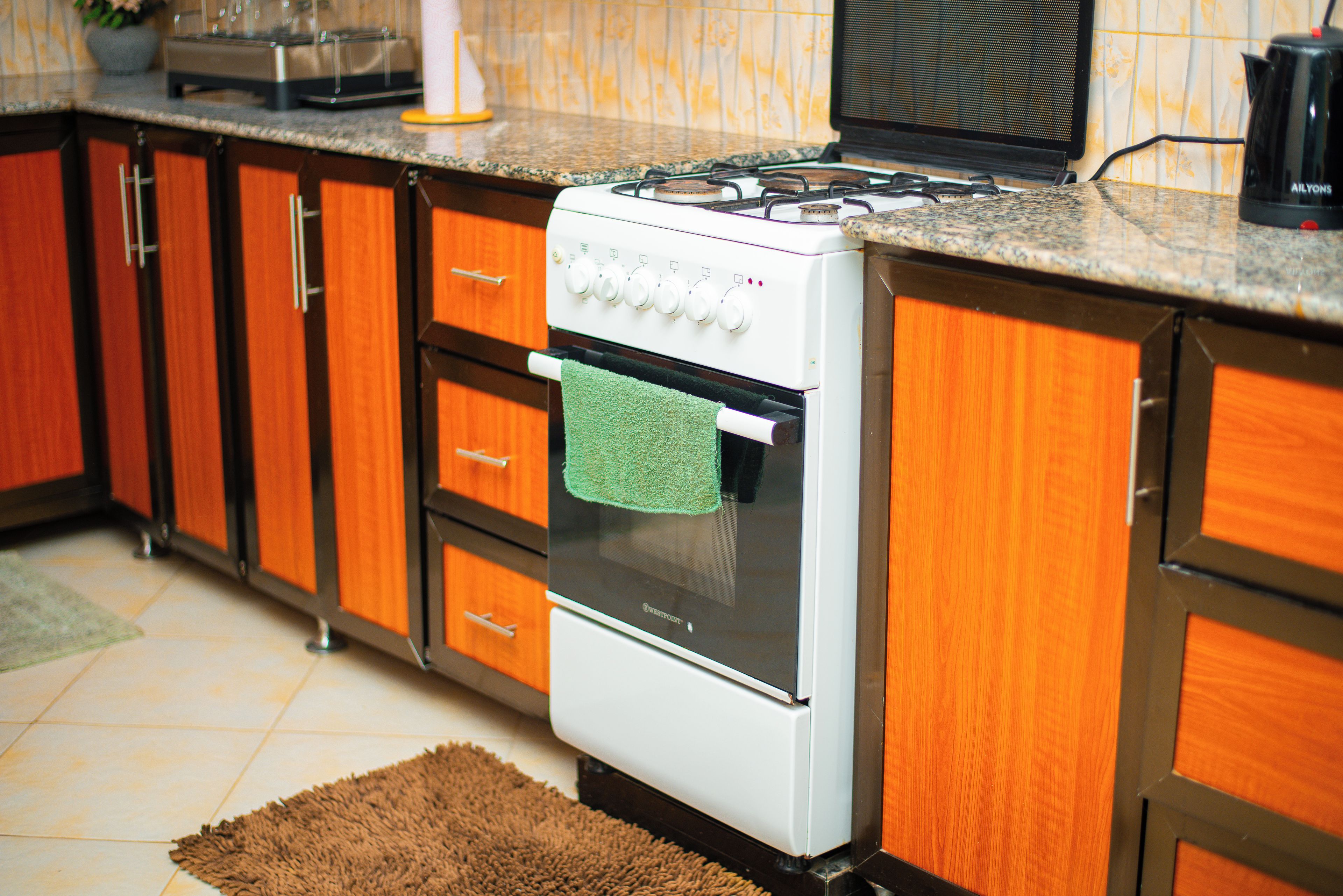 Una cocina con armarios de madera, una estufa blanca y un tapete marrón.