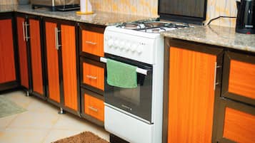 Una cocina con armarios de madera, una estufa blanca y un tapete marrón.