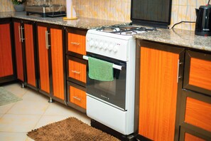 A kitchen with wooden cabinets, a white stove, and a brown rug.