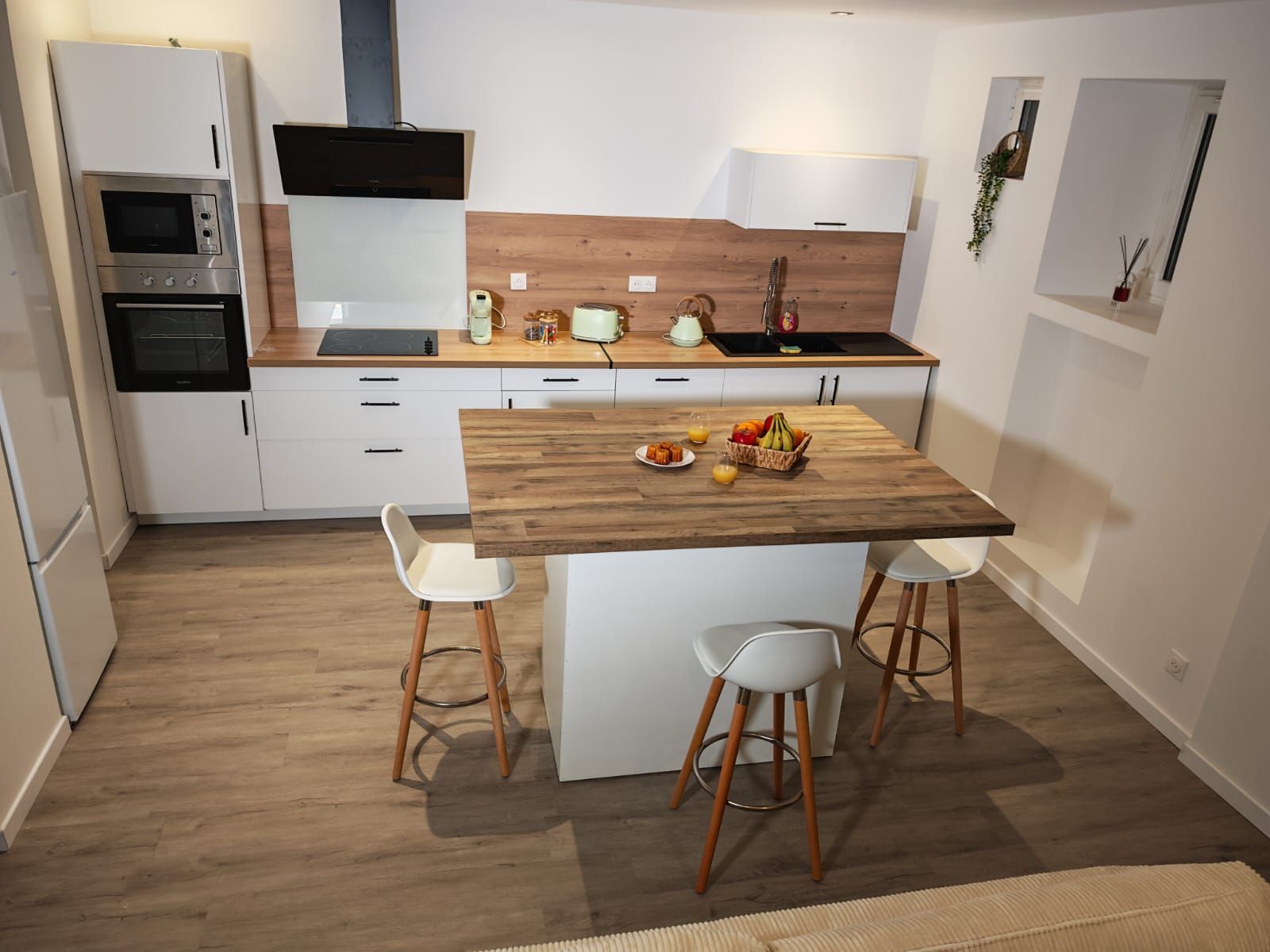 Una cocina moderna con una isla de madera, muebles blancos y electrodomésticos de acero inoxidable.