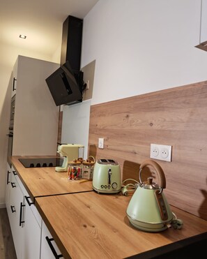Eine Küche mit einer Holzarbeitsplatte, einem Wasserkocher, einem Toaster und einer Lampe.