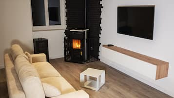 Una sala de estar moderna con un sofá seccional, una chimenea negra, un televisor montado en la pared y un estante de madera.